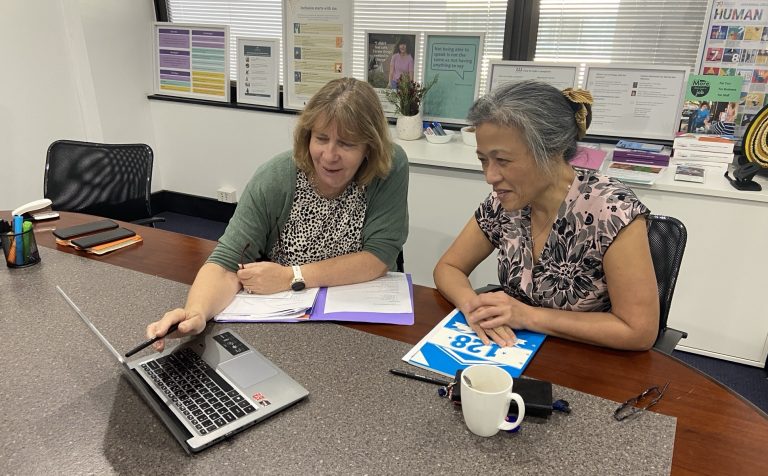 Two people working together at a laptop during an advocacy meeting