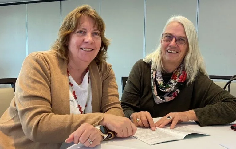 Two women smiling together while reviewing documents at a table